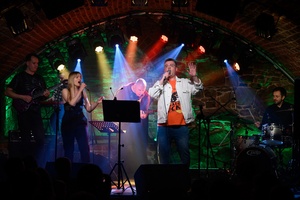 Koncert S.M.ROCK: na scenie nauczyciele S.M.ROCK wykonujący piosenkę. Na pierwszym planie śpiewający Weronika Kukla i Sławomir Ramian, w tle od lewej: gitarzysta Łukasz Wełna, pianista Piotr Niedojadło, basista Grzegorz Nosek, perkusista Sebastian Mnich