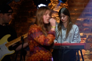 Koncert S.M.ROCK: na scenie śpiewająca uczennica, w tle uczennica grająca na instrumencie klawiszowy i uczeń grający na gitarze