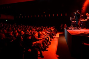 Koncert: Fisz Emade Tworzywo - Publiczność przed sceną, na scenie w tle basista Staszek Wróbel i na pierwszym planie wokalista Bartek Waglewski