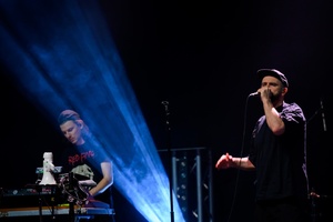 Koncert: Fisz Emade Tworzywo - Na scenie w tle basista Staszek Wróbel, na pierwszym planie wokalista Bartek Waglewski