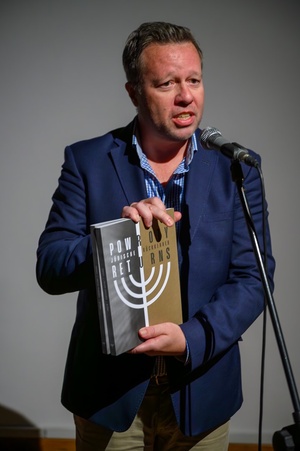 Wystawa: Powroty - Claus Heimes Dyrektor Instytutu Goethe'go w Krakowie podczas przemowy, prezentujący katalog do wystawy.