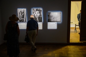 Wystawa: Powroty - Publiczność wernisażu oglądająca fotografie.