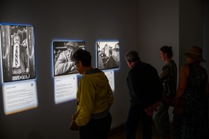 Wystawa: Powroty - Publiczność wernisażu oglądająca fotografie.