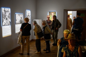 Wystawa: Powroty - Publiczność wernisażu oglądająca fotografie.