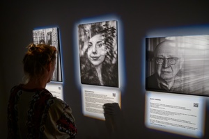 Wystawa: Powroty - Publiczność wernisażu oglądająca fotografie.