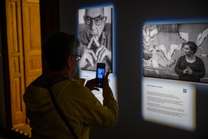 Wystawa: Powroty - Publiczność wernisażu oglądająca fotografie.