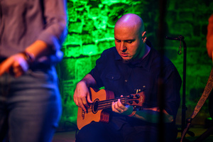 Koncert: Zaduszki - Scena w Piwnicach TCK. Grzegorz Nosek podczas gry na gitarze basowej.