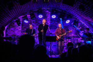 Koncert: Zaduszki - Scena w Piwnicach TCK. Rafał Huszno podczas występu, w tle Grzegorz Nosek i Paweł Mazur.