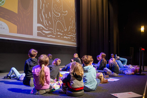 Filmowe ferie w kinie Marzenie - Na fotografii widzimy grupę dzieci na scenie przed ekranem, podczas animacji poprzedzających projekcje filmowe w ramach cyklu "Filmowe ferie".