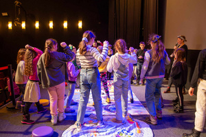 Filmowe ferie w kinie Marzenie - Na fotografii widzimy grupę dzieci na scenie przed ekranem, podczas animacji poprzedzających projekcje filmowe w ramach cyklu "Filmowe ferie".