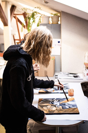 Artystyczne Ferie - tydzień I - Na zdjęciu przedstawione są dzieci uczestniczące w warsztatach plastycznych, skupione na malowaniu i rysowaniu. Widoczne są również osoby prowadzące, które instruują i inspirują młodych uczestników, zachęcając ich do twórczej ekspresji