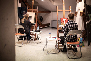 Artystyczne Ferie - tydzień I - Na zdjęciu przedstawione są dzieci uczestniczące w warsztatach plastycznych, skupione na malowaniu i rysowaniu. Widoczne są również osoby prowadzące, które instruują i inspirują młodych uczestników, zachęcając ich do twórczej ekspresji