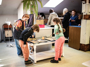 Artystyczne Ferie - tydzień I - Na zdjęciu przedstawione są dzieci uczestniczące w warsztatach plastycznych, skupione na malowaniu i rysowaniu. Widoczne są również osoby prowadzące, które instruują i inspirują młodych uczestników, zachęcając ich do twórczej ekspresji