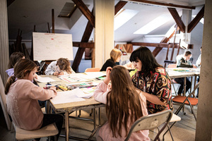 Artystyczne Ferie - tydzień I - Na zdjęciu przedstawione są dzieci uczestniczące w warsztatach plastycznych, skupione na malowaniu i rysowaniu. Widoczne są również osoby prowadzące, które instruują i inspirują młodych uczestników, zachęcając ich do twórczej ekspresji