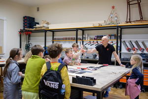 Naukowe Ferie w Pasażu Odkryć - Na zdjęciu przedstawieni są uczestnicy – dzieci i młodzież – zaangażowani w aktywności edukacyjne w różnych pracowniach naukowych, takich jak chemiczna, stolarska, planetarium oraz informatyczna. Widoczne są sceny, gdzie uczą się i przeprowadzają eksperymenty pod nadzorem instruktorów.