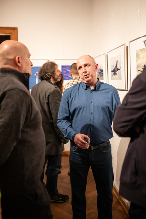 Wernisaże dzień po dniu: Paweł Wadas / Krzysztof Madej - Zdjęcie z otwarcia wystawy w Galerii TCK. Przedstawia uczestników wernisażu, skupionych w oglądaniu prac i rozmowach z autorami. Fotografia ukazuje dynamiczną atmosferę wydarzenia.