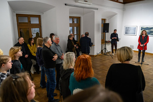 Wernisaż wystawy Autoportret Naturalnie - Inez Baturo przemawia podczas otwarcia wystawy, na pierwszym planie publiczność zgromadzona w sali.