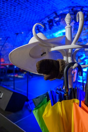 Koncert: Pracownia piosenki prezentuje - Niepozorny zaścianek - Zdjęcie przedstawia scenografię koncertu. Biały wieszak z rekwizytami używanymi podczas koncertu t.j. kapelusz, parasolka, rękawiczki.