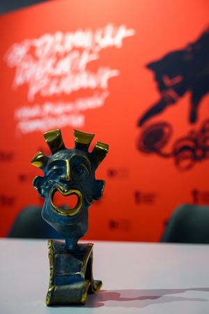 Konferencja prasowa 38. TNF - Statuetka Maszkarona na tle wizualizacji festiwalu