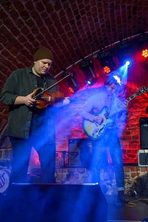 Koncert jazzowy: Tomasz Chyła Quintet - Zdjęcie sceny z koncertu Tomasz Chyła Quintet, pokazujące zaangażowanych muzyków. Tomasz Chyła gra na skrzypcach, w tle pozostali muzycy na różnych instrumentach. Scena jest dynamicznie oświetlona, co dodaje energii występowi.