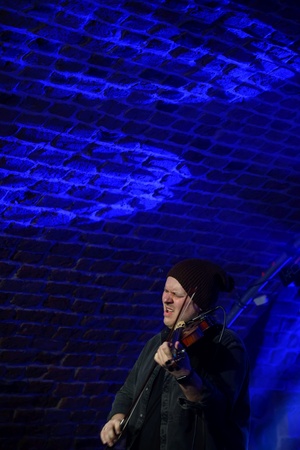 Koncert jazzowy: Tomasz Chyła Quintet - Zdjęcie sceny z koncertu Tomasz Chyła Quintet, pokazujące zaangażowanych muzyków. Tomasz Chyła gra na skrzypcach, w tle pozostali muzycy na różnych instrumentach. Scena jest dynamicznie oświetlona, co dodaje energii występowi.