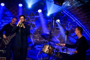 Koncert jazzowy: Tomasz Chyła Quintet - Zdjęcie sceny z koncertu Tomasz Chyła Quintet, pokazujące zaangażowanych muzyków. Tomasz Chyła gra na skrzypcach, w tle pozostali muzycy na różnych instrumentach. Scena jest dynamicznie oświetlona, co dodaje energii występowi.