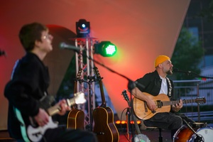 Koncert: Skubas - Duet Akustycznie - Na amfiteatralnej scenie grający na gitarach i śpiewający Marcin Grabiński i Skubas