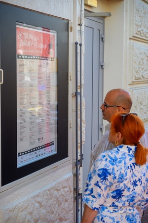 38. TNF - Dzień 3 (2.06.2024) - Widzowie czytający plakat z programem 38. TNF