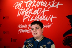 38. TNF - Dzień 6 (5.06.2024) - Odtwórca głównej roli w filmie "Za duży na bajki 2" Maciej Karaś na tle ścianki festiwalowej w Marzeniu