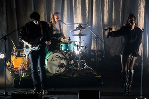 Koncert: Kasia Lins - Na scenie od lewej: grający na gotarze Karol Łakomiec, grająca na perkusji i śpiewająca chórki Wiktoria Jakubowska, Kasia Lins w interakcji z publicznością