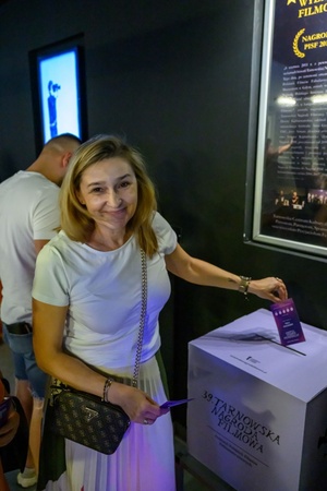 39. TNF: Dzień 3 (1.06.2025) - W hallu kina festiwalowiczka oddająca swój głos wrzucając wypełniony kupon plebiscytowy