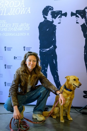 39. TNF: Dzień 3 (1.06.2025) - Reżyserka Olga Chajdas z psem Nioki na tle ścianki festiwalowej w hallu Marzenia