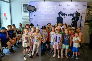 39. TNF: Dzień 4 (2.06.2025) - W hallu Marzenia najmłodsi widzowie przed pierwszą projekcją konkursową Filmów Młodego Widza fotografowani na ściance 39. TNF