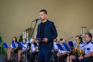 Koncert Polskiej Muzyki Rozrywkowej - Orkiestra Dęta Grupy Azoty S.A. i soliści - Na scenie prowadzący koncert Tomasz Lizak przemawiający do publiczności