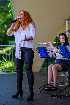 Koncert Polskiej Muzyki Rozrywkowej - Orkiestra Dęta Grupy Azoty S.A. i soliści - Na scenie śpiewająca solistka Magdalena Stalmach z grającą flecistką orkiestry dętej w tle