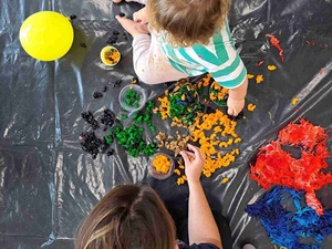 Warsztaty sensoplastyczne - Uczestnik warsztatów wraz z opiekunem podczas zabawy kolorowym makaronem