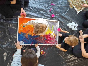 Warsztaty sensoplastyczne - Uczestnicy warsztatów wraz z opiekunami podczas zabawy kolorowym ryżem