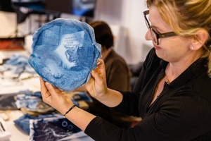 Warsztaty fotograficzne: cyjanotypia - Uczestniczka prezentująca efekt swojej pracy ze zdjęciem odbitym na materiale.