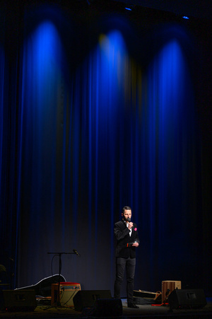 Koncert: Adam Nowak i Akustyk Amigos - Zapowiedź koncertu. Na scenie konferansjer Sebastian Szafarz.